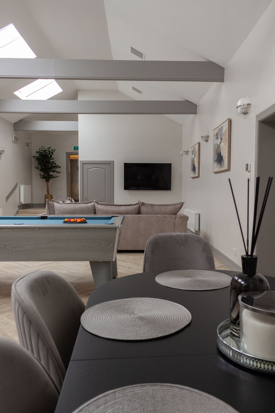 Open-plan lounge with a pool table, corner sofa and skylights, in a home we look after in Dalkeith