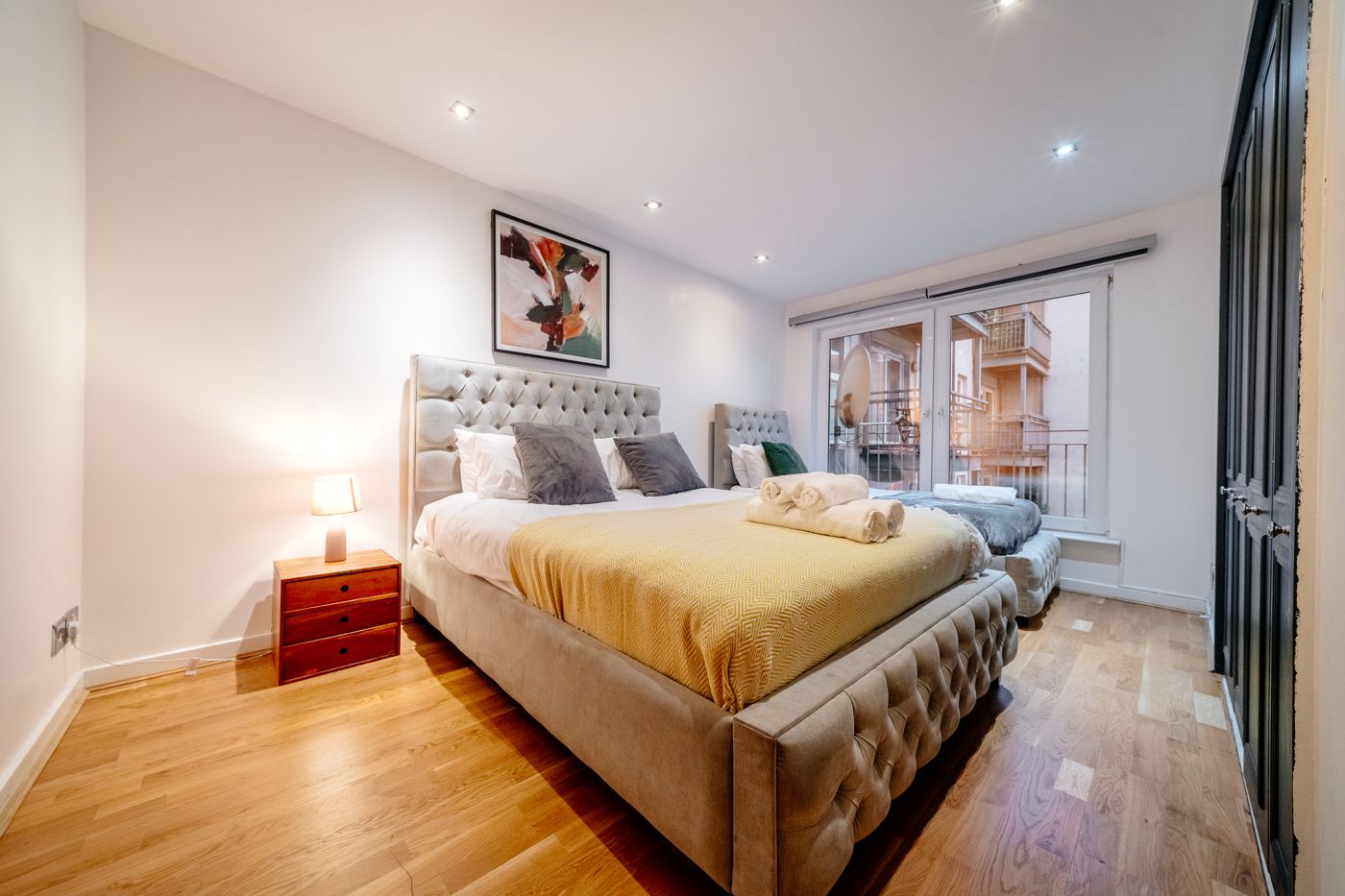 Bedroom with a king-size and a second bed, a mustard throw and rolled towels, near Easter Road