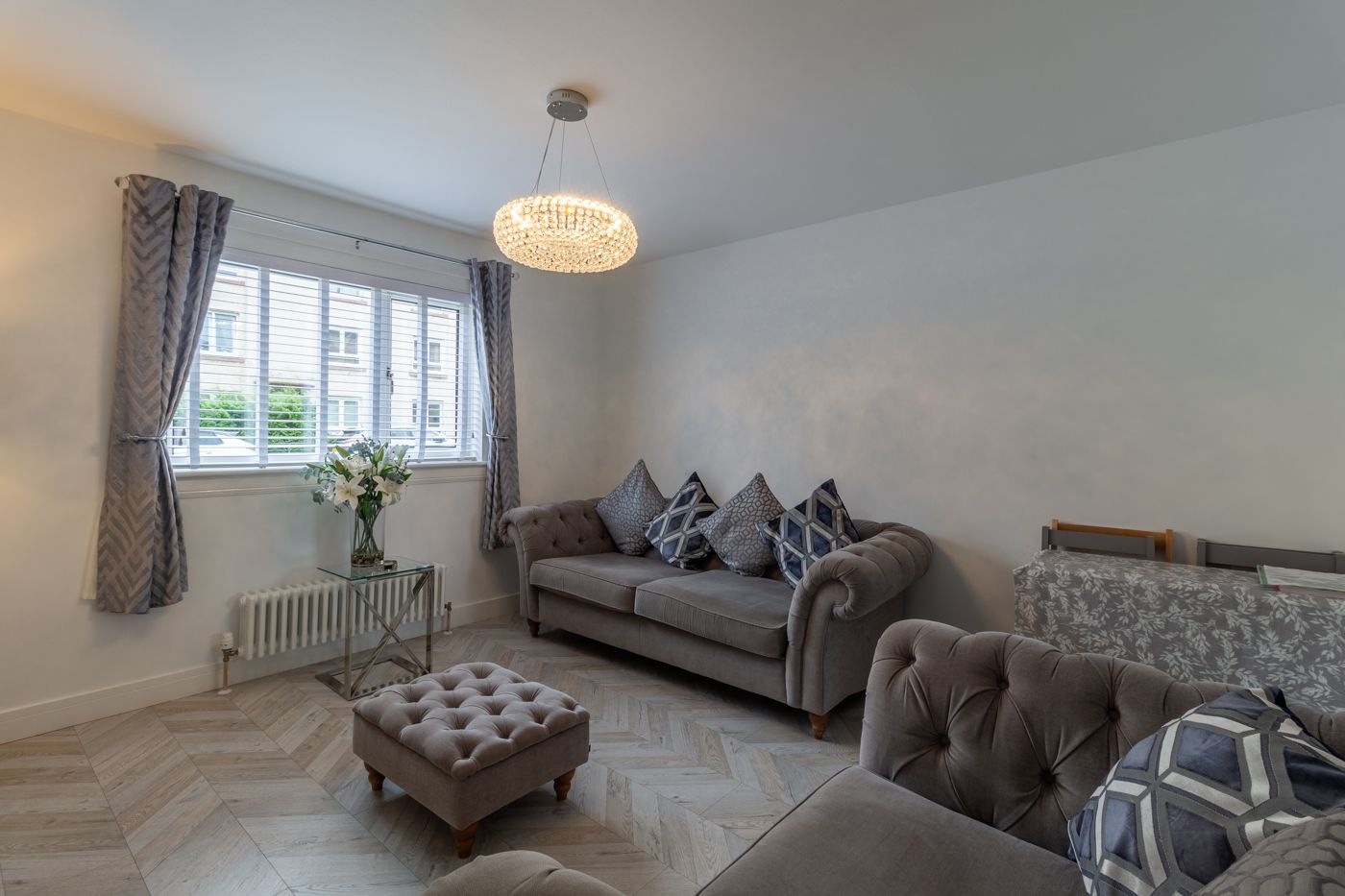 Grey velvet Chesterfield sofa and footstool by the window, in Prestonfield
